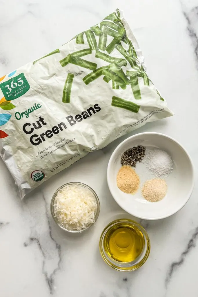 A bag of cut green beans, spices, grated parmesan cheese, and olive oil.