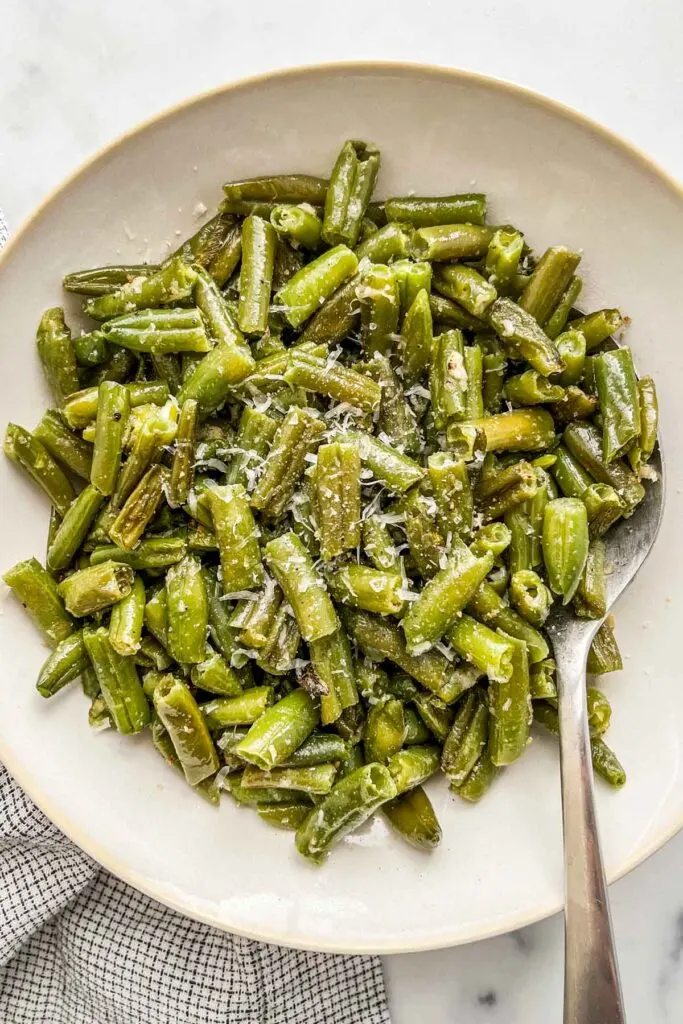 Roated frozen green beans topped with parmesan in a serving bowl.