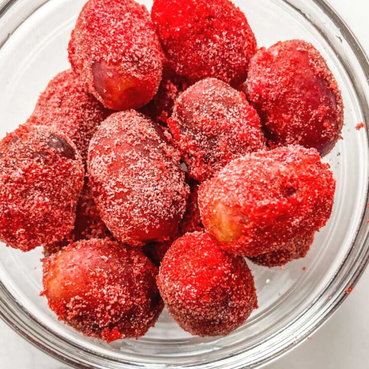 Sour candy frozen grapes in a glass bowl.