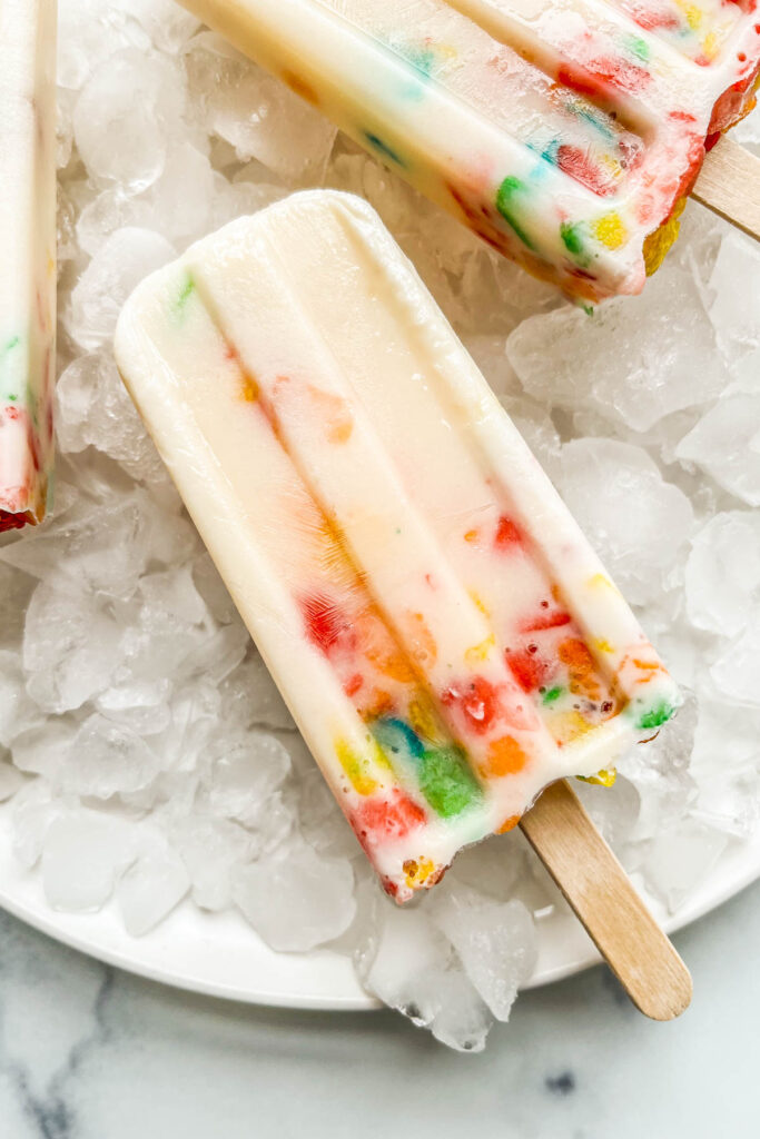 Cereal milk popsicles on a plate with ice.