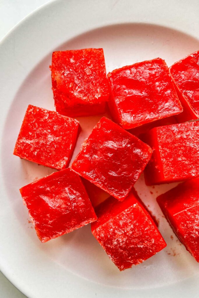 Frozen cherry jello pieces on a white plate.