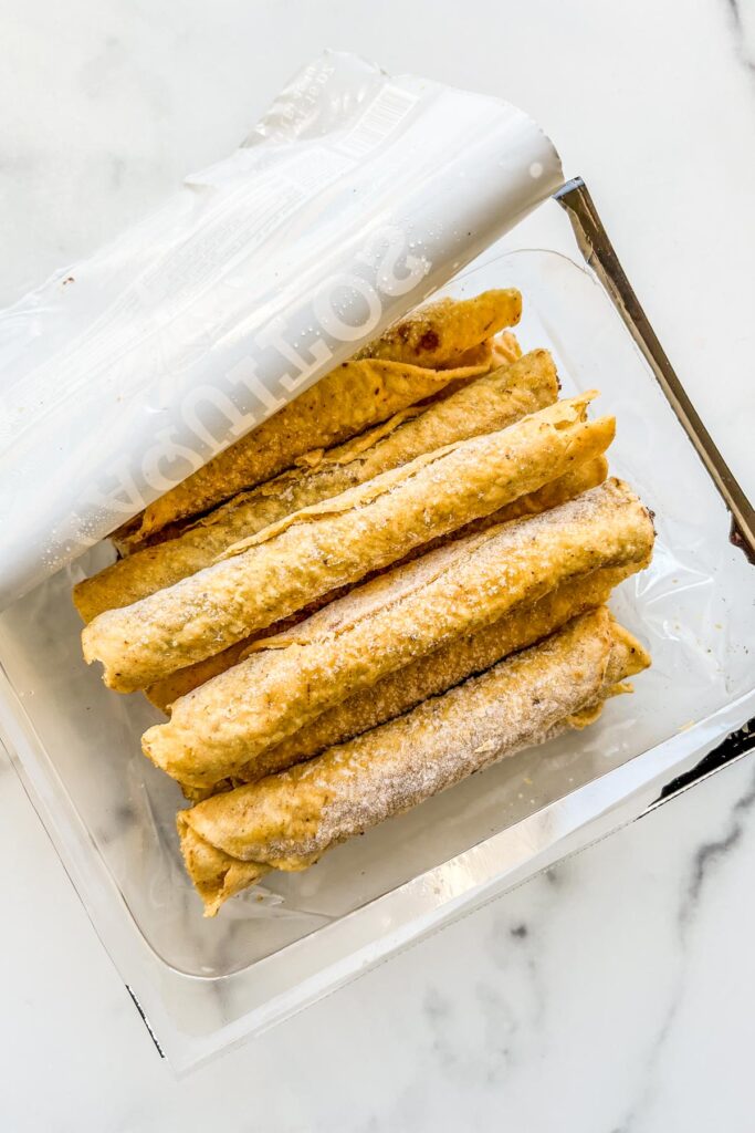 Frozen taquitos in a plastic container.